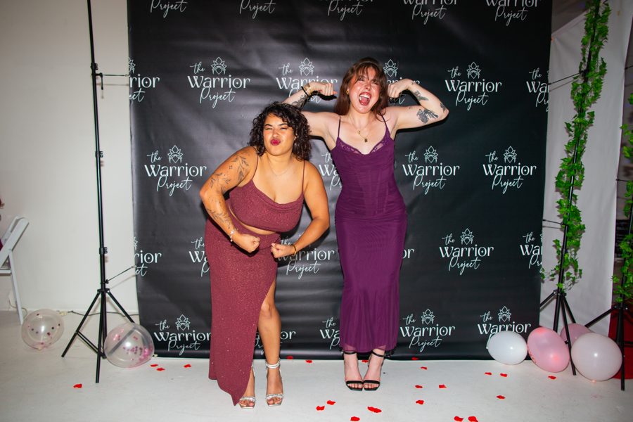 Two members in gowns on the Warrior Project step-and-repeat backdrop