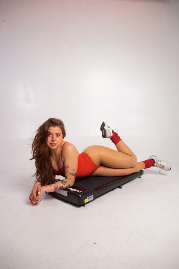 Red bodysuit posing on a walking pad in the studio